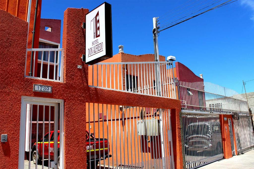 um edifício vermelho com um sinal na lateral em Hotel Don Alfredo em Calama