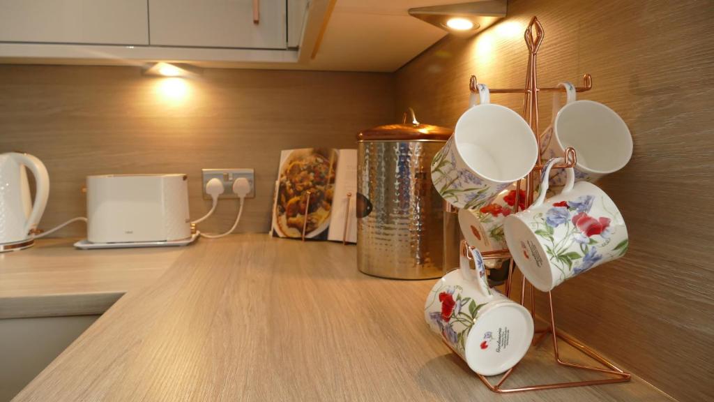 a kitchen counter with white dishes hanging from a wall at Riverside Apartments in Carluke