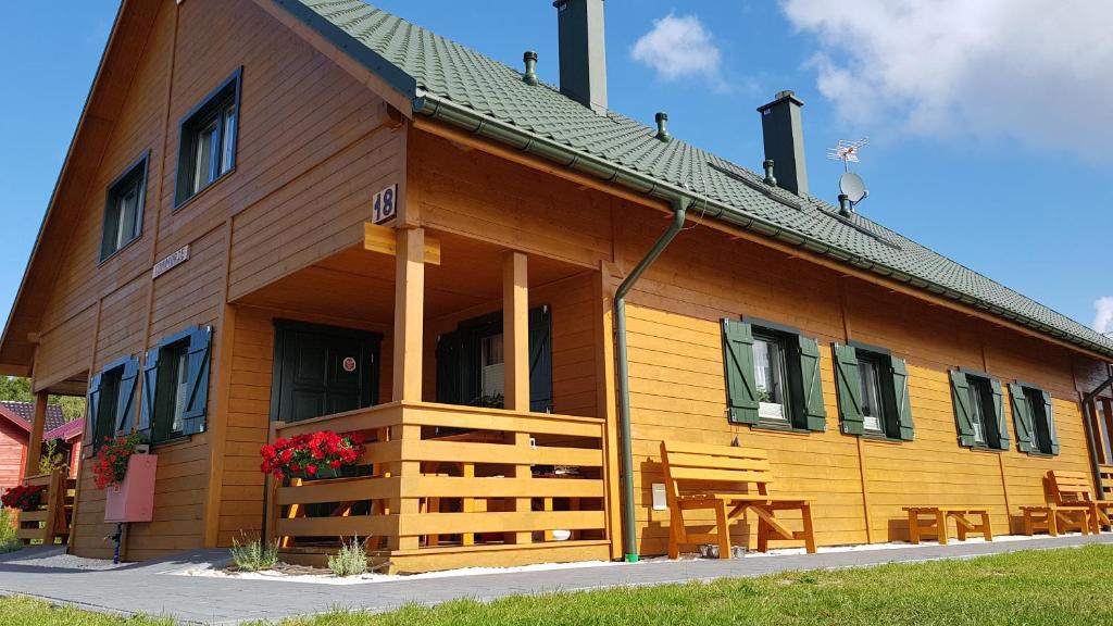 una gran casa de madera con sillas delante en Szumimorze, en Rusinowo