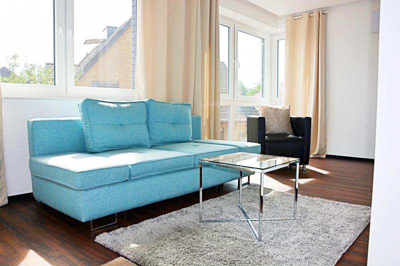 a living room with a blue couch and a table at X-Hotel in Emsdetten