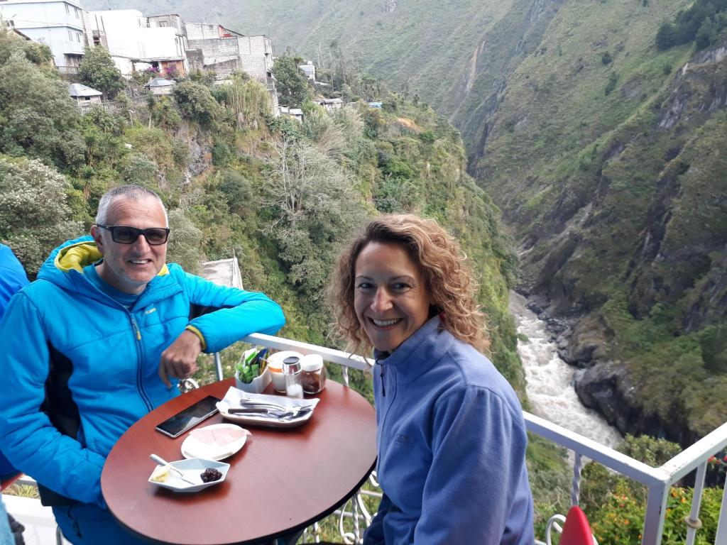 a man and woman sitting at a picnic table at Hostal Balcon del Cielo in Baños