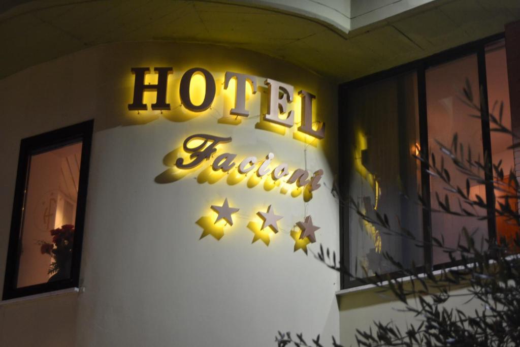uma placa de hotel de néon na lateral de um edifício em Hotel Facioni em Pomezia