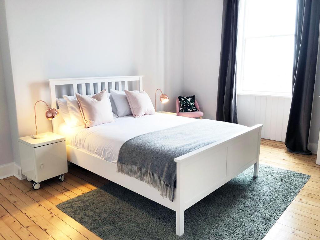 um quarto com uma cama branca e uma janela em Stylish City Centre Apartments - D Terrace Residence em Edimburgo