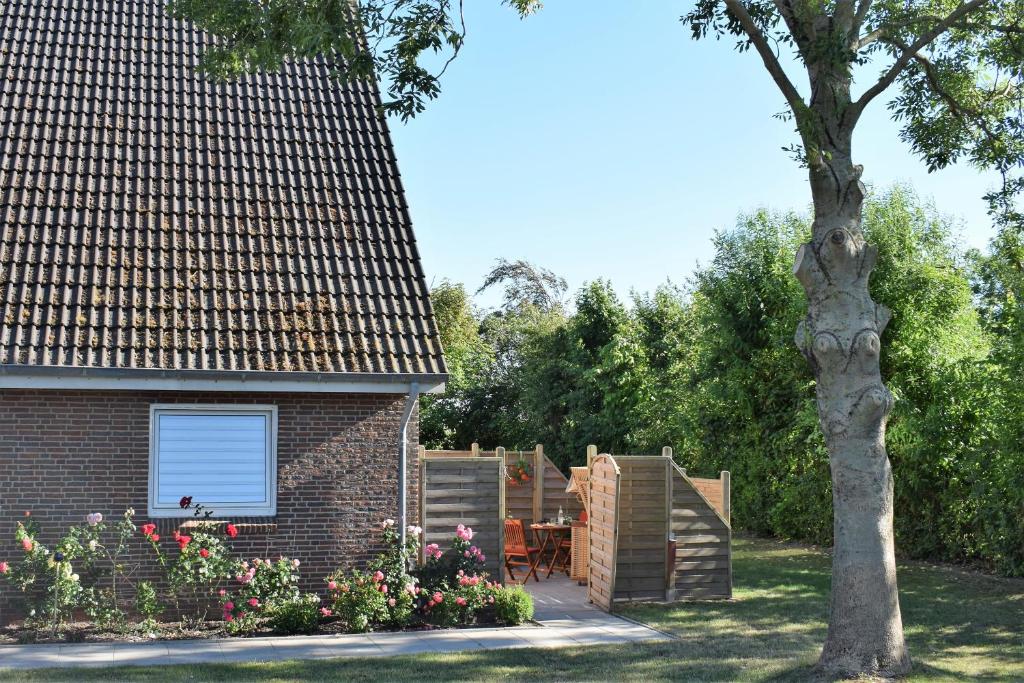 a backyard with a brick house and a tree at Rote Koje in Dagebüll