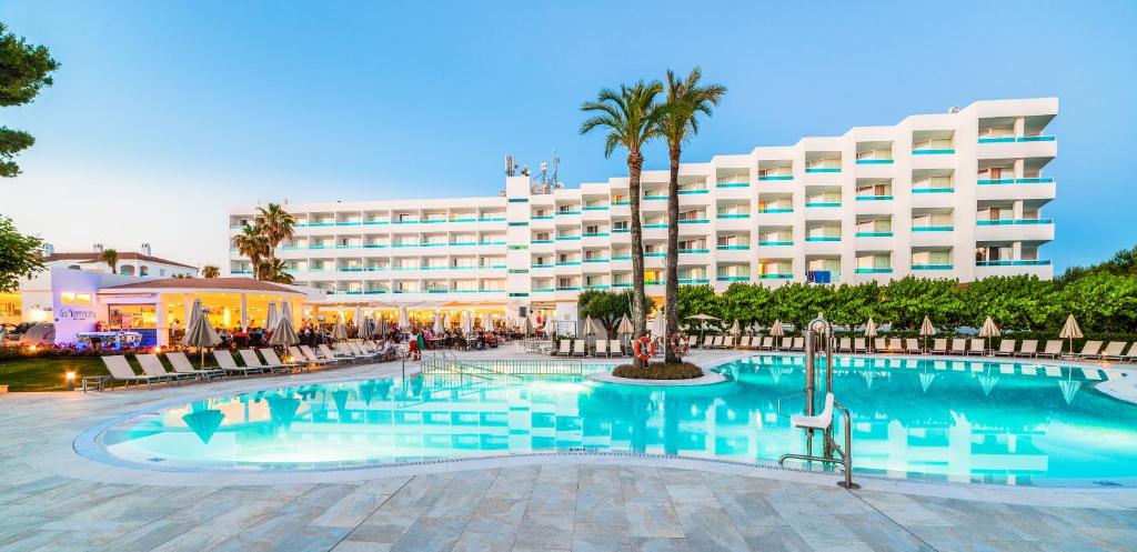 カラ・ブランカにあるGlobales Mediterraniの建物の前にスイミングプールがあるホテル
