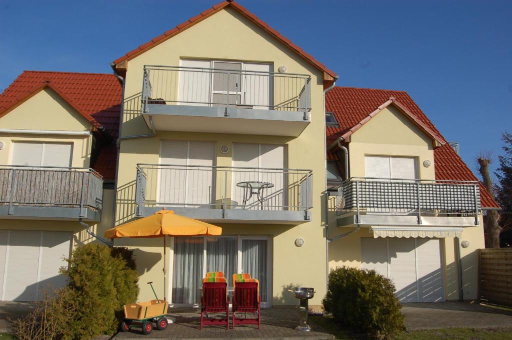 budynek z krzesłami i pomarańczowym parasolem przed nim w obiekcie Zum Sonnenuntergang w Zingst