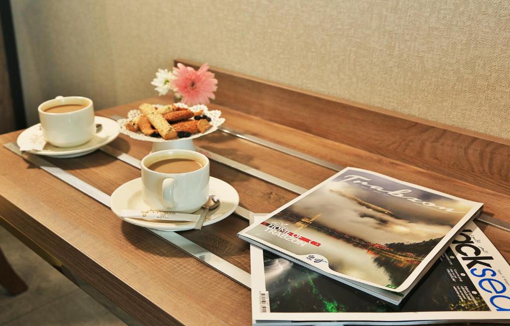 a table with two cups of coffee and a magazine at Yildiz Life Hotel in Trabzon
