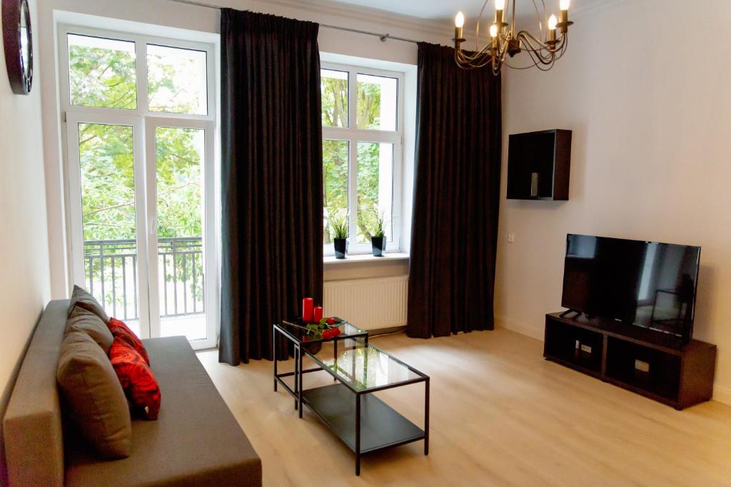uma sala de estar com um sofá e uma televisão em Apartament Różany em Gorzów Wielkopolski