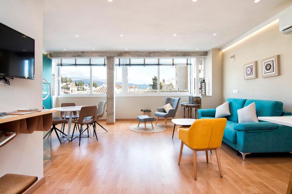 Una sala de estar con un sofá azul y sillas. en tuGuest Clave de Sol Apartment, en Granada
