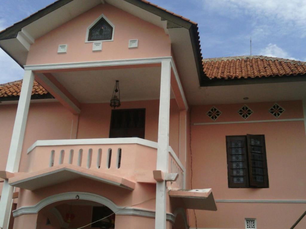 ein rosafarbenes Haus mit einer Veranda und einem Balkon in der Unterkunft Kost 48 Surabaya in Surabaya