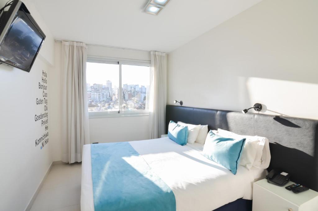 a bedroom with a bed with blue pillows and a window at Cyan Recoleta Hotel in Buenos Aires