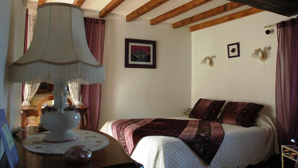 a bedroom with a bed and a lamp on a table at Chambres d&#39;hôtes La Hulotte 69 in Villechenève