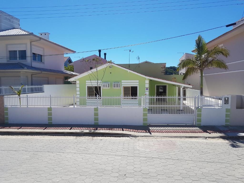una casa amarilla y verde con una valla blanca en Casa incrível a Beira Mar! 3 qtos Ponta do Papagaio, en Palhoça