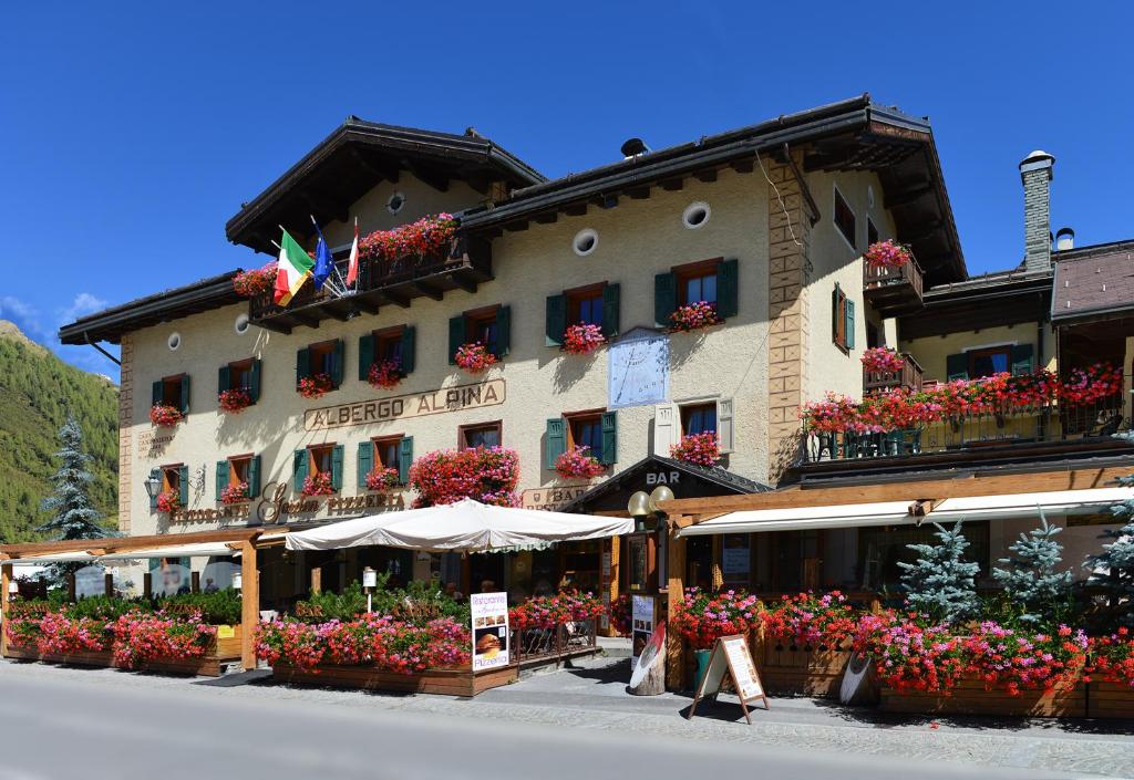 un grande edificio con fiori di fronte di Hotel Alpina a Livigno