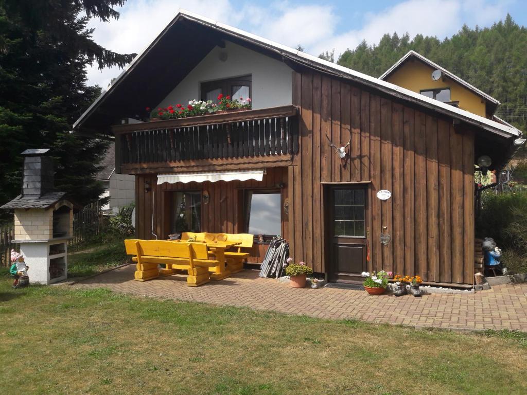une maison avec une terrasse dotée d'une table et d'un banc dans l'établissement Ferienhaus Panoramablick, à Piesau