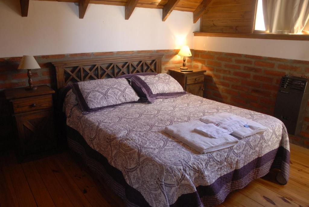 1 dormitorio con 1 cama con toallas en Cabañas Abelard en Esquel