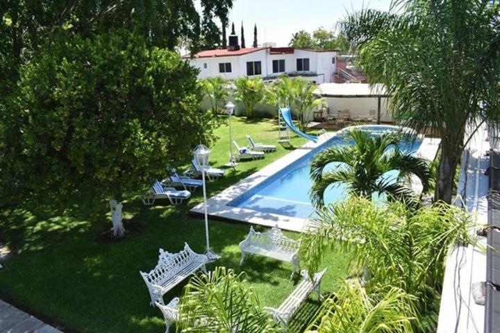 uma vista sobre uma piscina com cadeiras e árvores em Finca de los Angeles em Chiconcuac