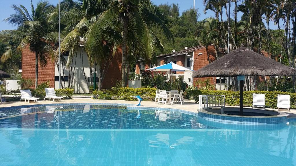 uma grande piscina com cadeiras e um guarda-sol em Casa Melo 4 em Ubatuba