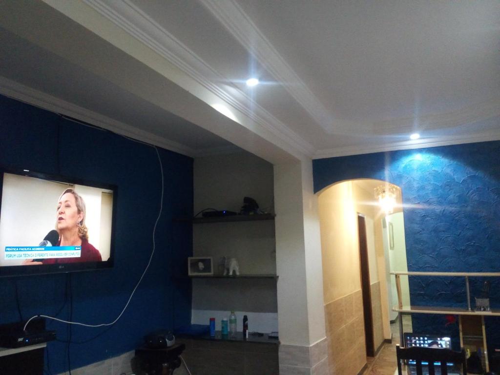 een woonkamer met een flatscreen-tv aan de muur bij Pousada Expominas in Belo Horizonte