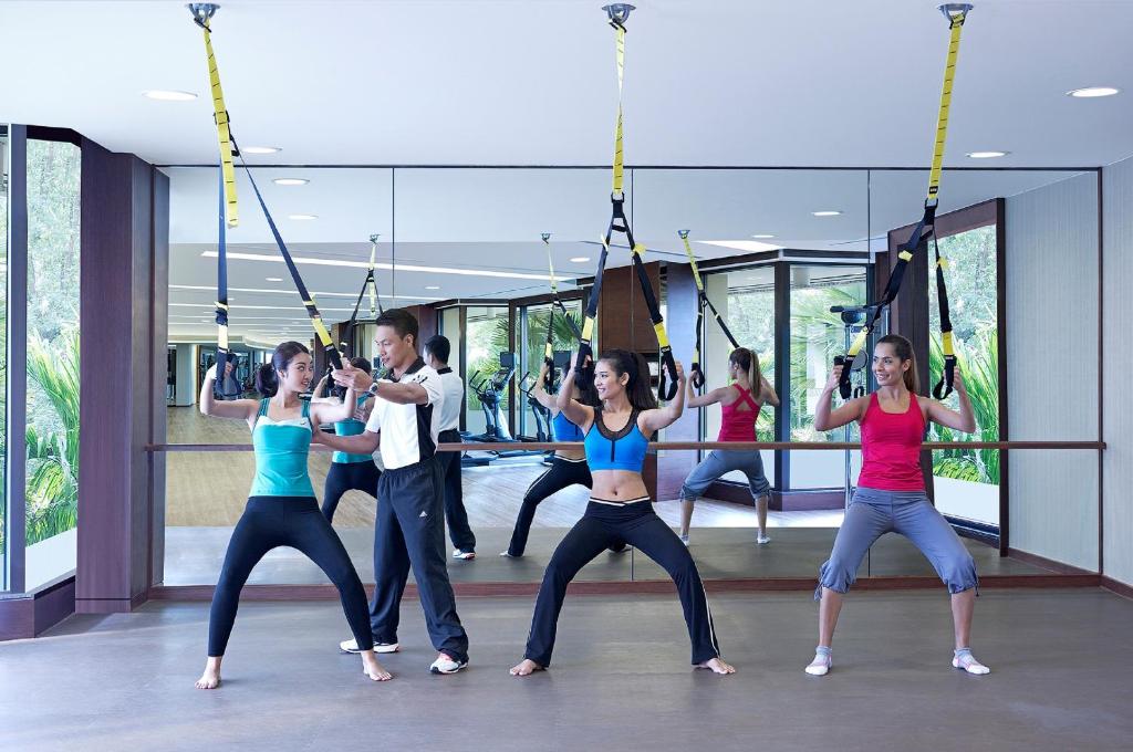 A mirrored studio where guests are taking part in a suspension-training class.