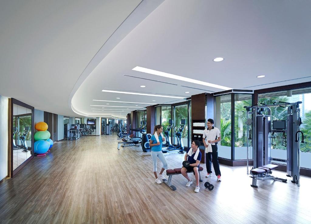 A spacious, bright gym with cardio equipment, weight machines, free weights, and mirrored walls.