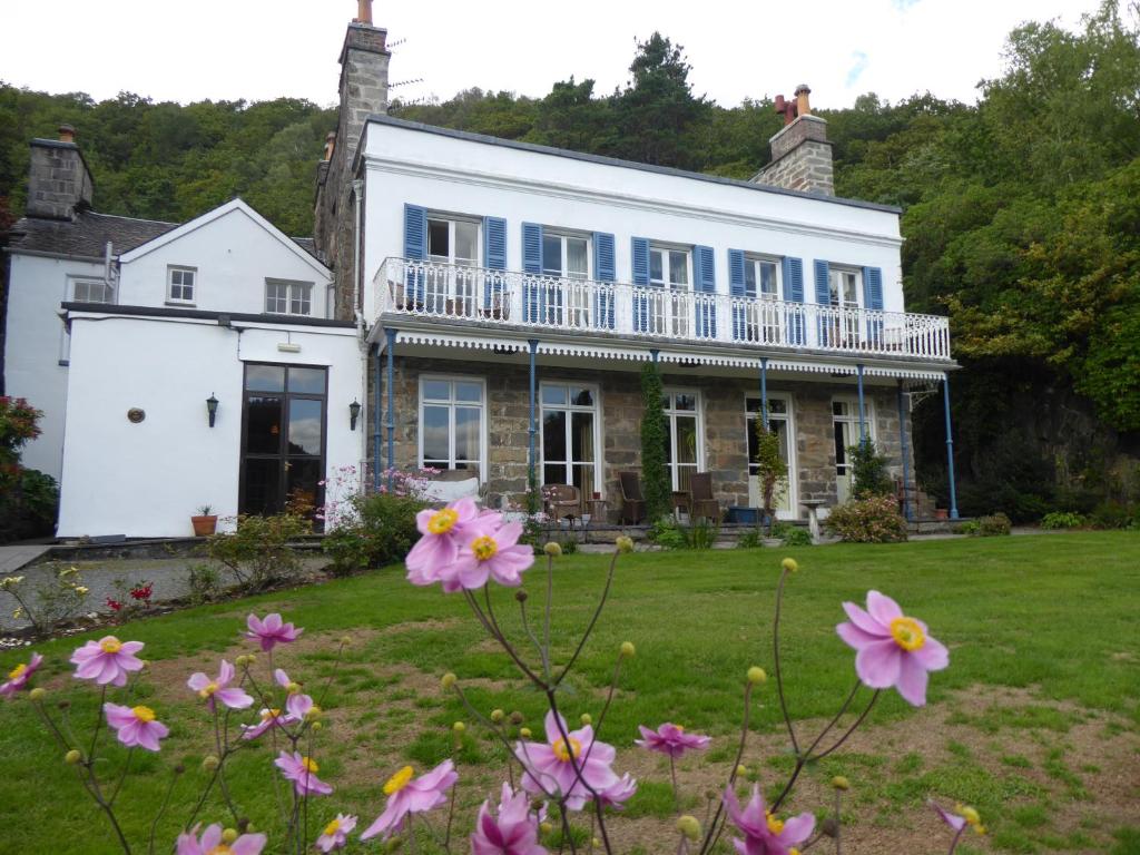 a white house with pink flowers in the yard at Borthwnog Hall in Dolgellau