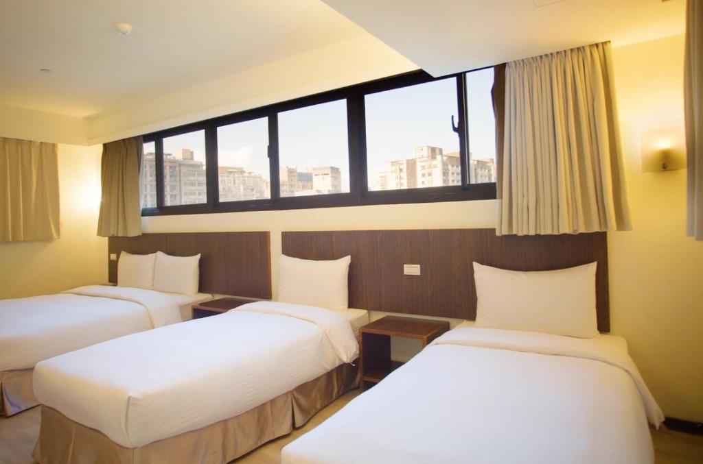 a hotel room with three beds and a window at Green World Sansui in Taipei