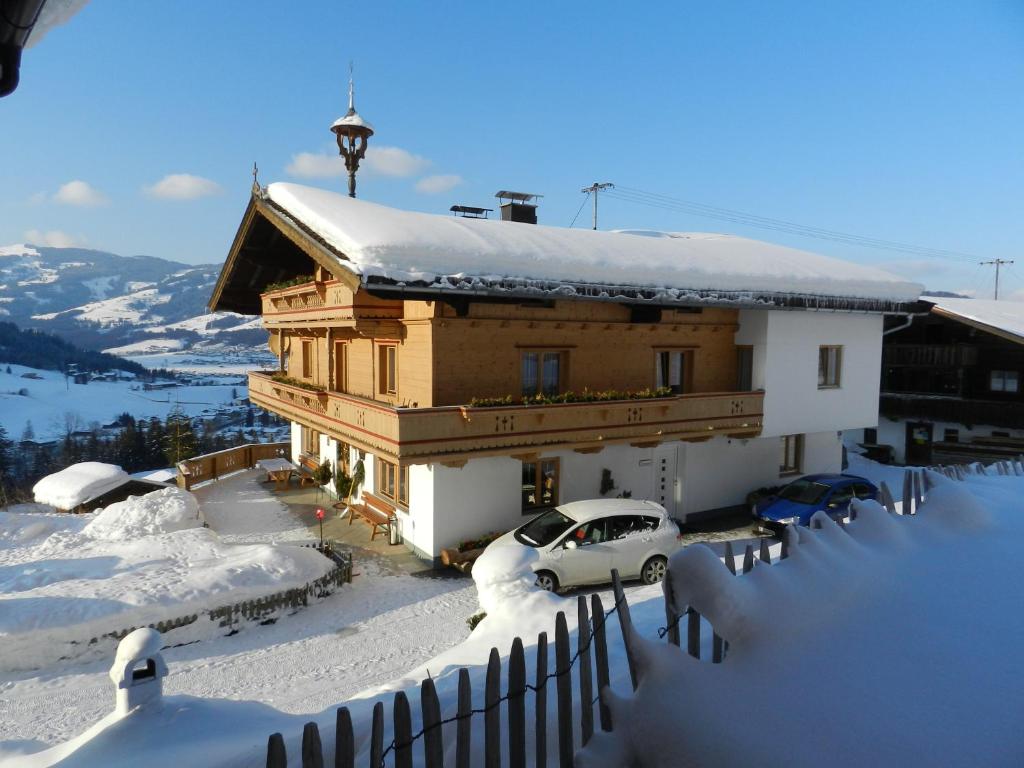 una casa cubierta de nieve con coches aparcados delante en Grillinghof, en Kirchberg in Tirol