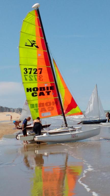 een zeilboot op het strand met mensen erop bij Malibu Beach in Koksijde
