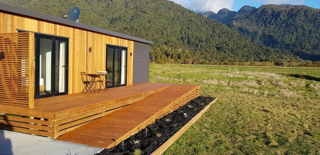 une maison avec une terrasse munie d'une table. dans l'établissement Alpine Escape, à Franz Josef