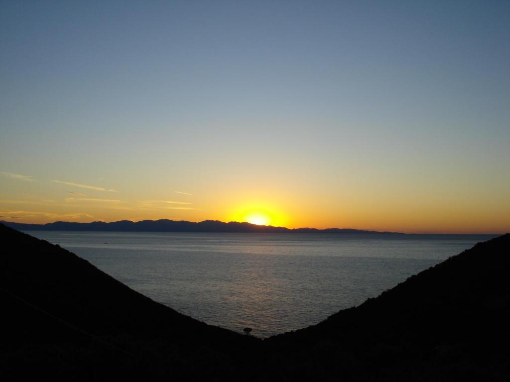 um pôr-do-sol sobre a água com o pôr-do-sol ao fundo em Hotel Villa Rita em Marciana