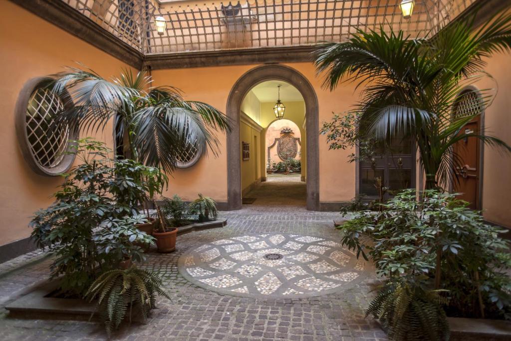 une cour intérieure avec des palmiers dans un bâtiment dans l'établissement Dimoro Suite, à Rome