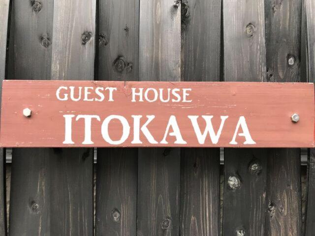 松崎町にあるゲストハウス・ イトカワのゲストハウスの水平線を持つ柵の木製看板