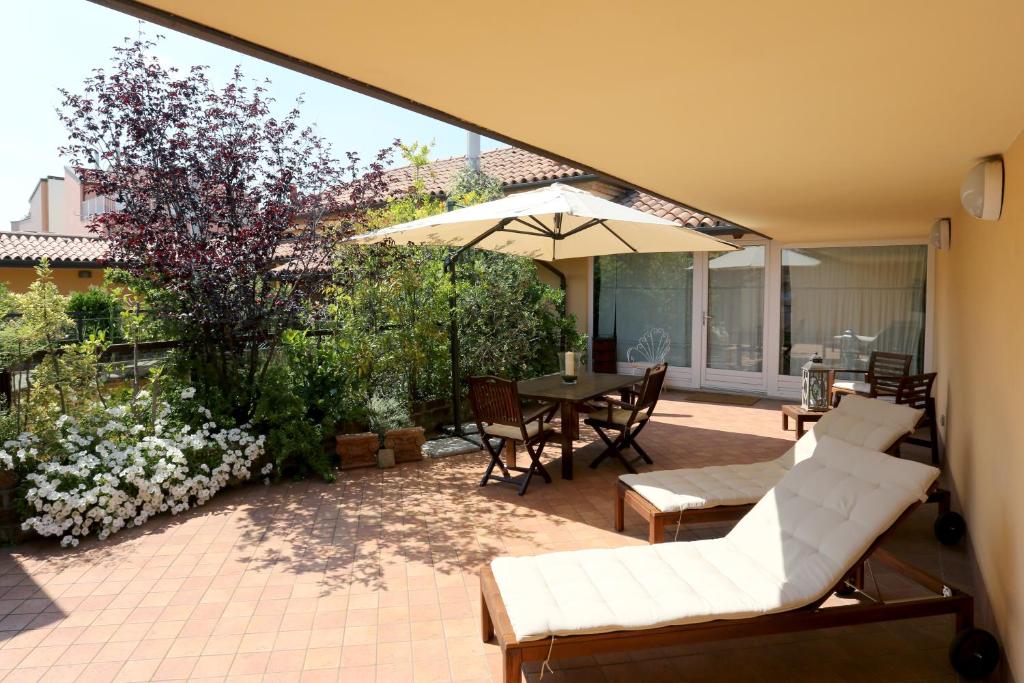 a patio with a table and chairs and an umbrella at Exclusive Aparthotel La Reunion in Ravenna