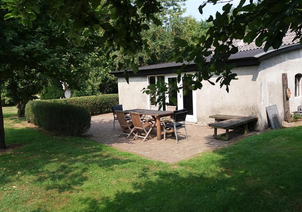 un patio con mesa, sillas y banco en La Lune De Boomgaard en Tripscompagnie