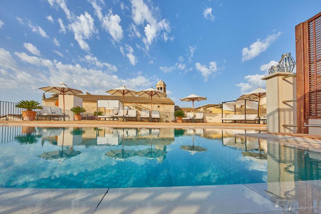 Una gran piscina con agua azul y sombrillas. en Cas Comte Suites & Spa - Adults Only, en Lloseta
