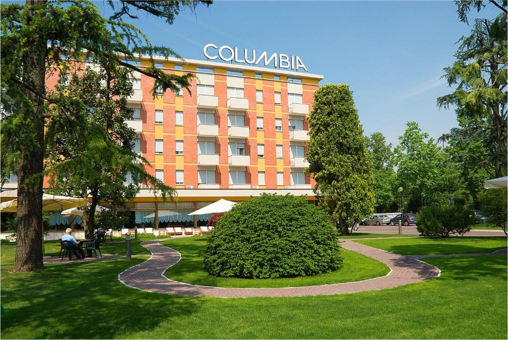 un hotel con un cespuglio di fronte a un edificio di Hotel Columbia Terme ad Abano Terme