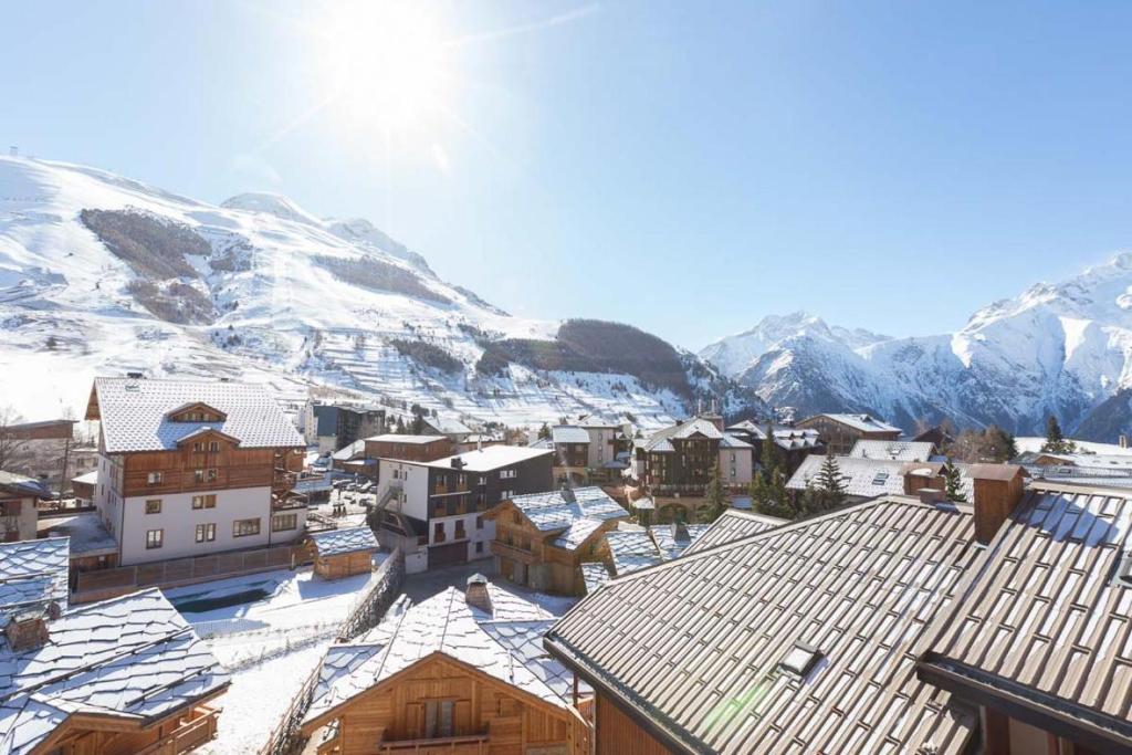a town with snow covered roofs in front of a mountain at Vacanceole - Résidence Andromede in Les Deux Alpes