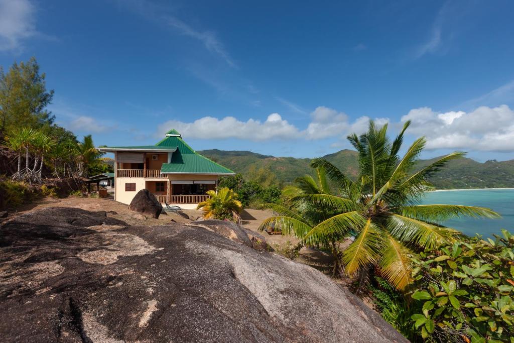 a house with a green roof on top of a rock at La Villa Mille Etoiles in Baie Sainte Anne