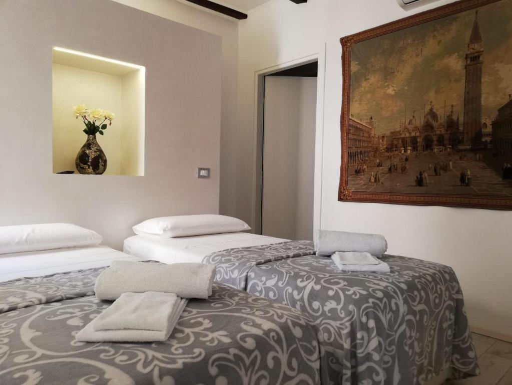two beds in a room with a painting on the wall at Ca' Zuliani Rooms in Chioggia