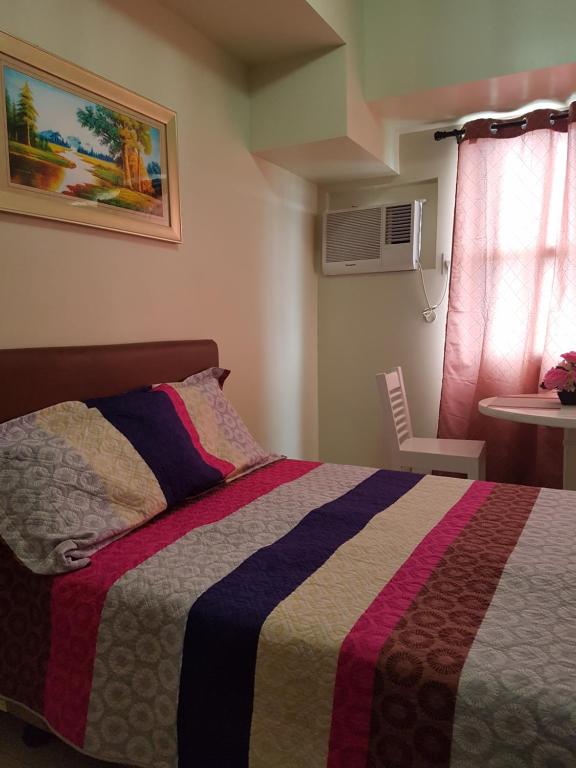 a bedroom with a bed with a colorful blanket at KC Studio 2 at Horizon 101 Cebu in Cebu City