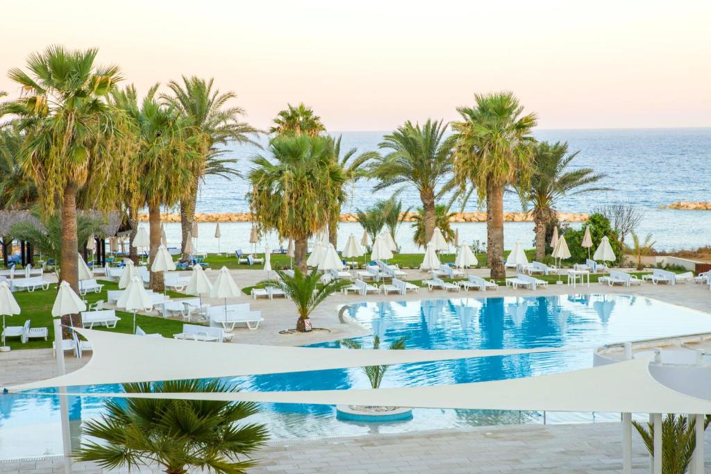 Blick auf ein Resort mit Pool und Palmen in der Unterkunft Venus Beach Hotel in Paphos City