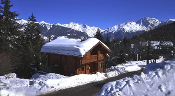 a wooden cabin with snow on top of a mountain at Chalet POMMAT in La Tania