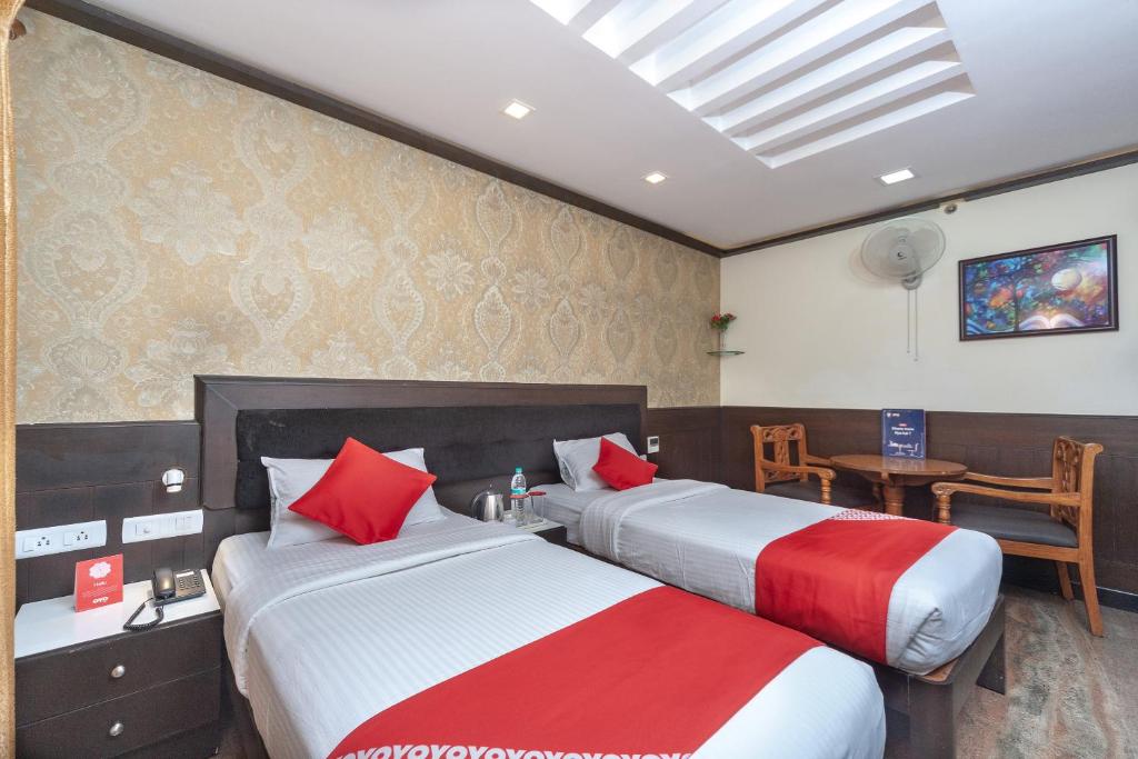 Dos camas en una habitación de hotel con rojo y blanco en Hotel Sumi Palace, en Thanjāvūr
