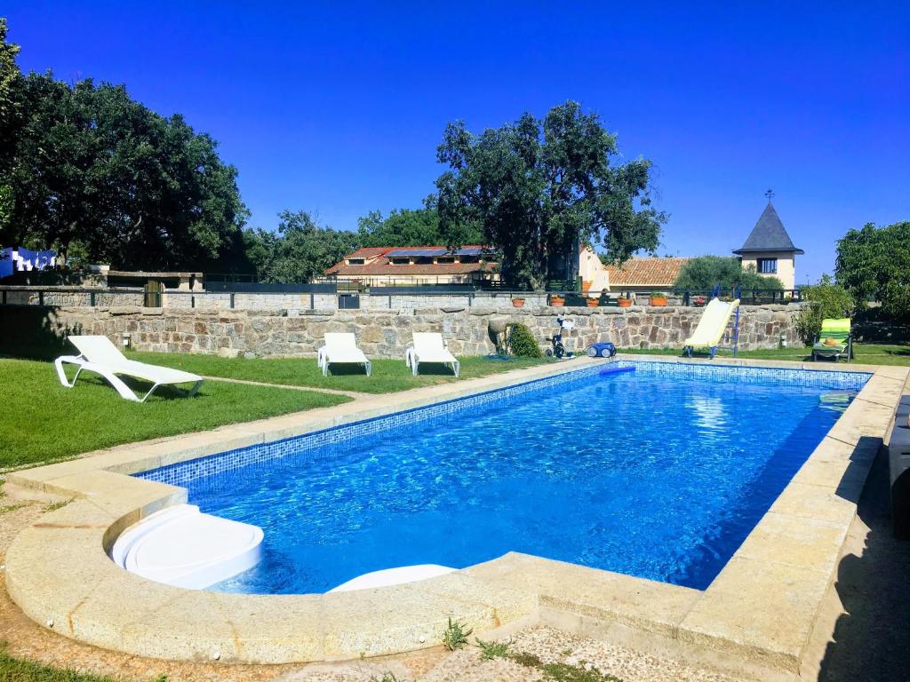 una piscina con 2 tumbonas en un patio en B&B Yeguada La Parrilla, en El Escorial