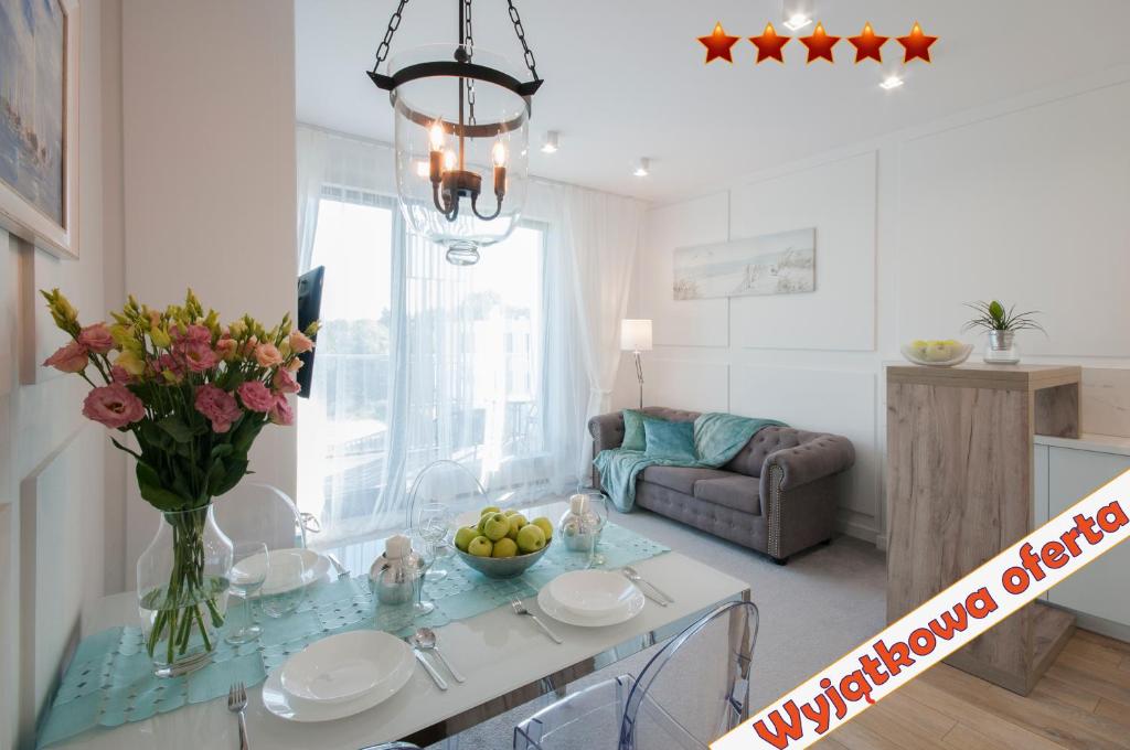 Elegance Sopot Gdynia Apartment في سوبوت: غرفة معيشة مع طاولة مع إناء من الزهور