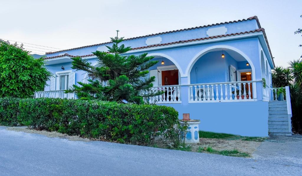 een blauw huis met een balkon en een boom bij Vicky's Village private House in Fiolítis