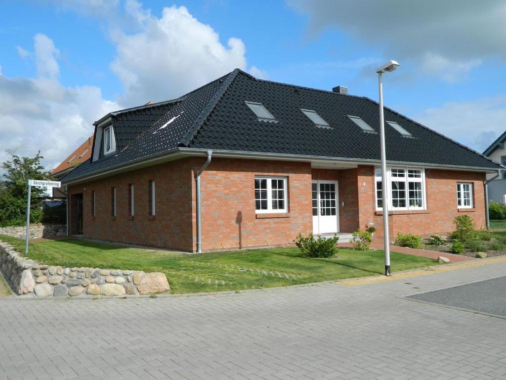 ein rotes Backsteinhaus mit schwarzem Dach in der Unterkunft Deichgraf in Husum