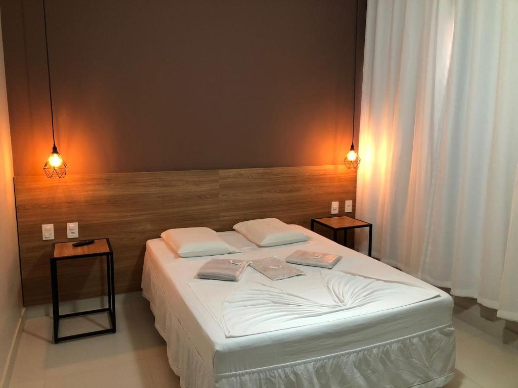 um quarto com uma cama branca e duas mesas em Hotel Beira Rio em Teófilo Otoni