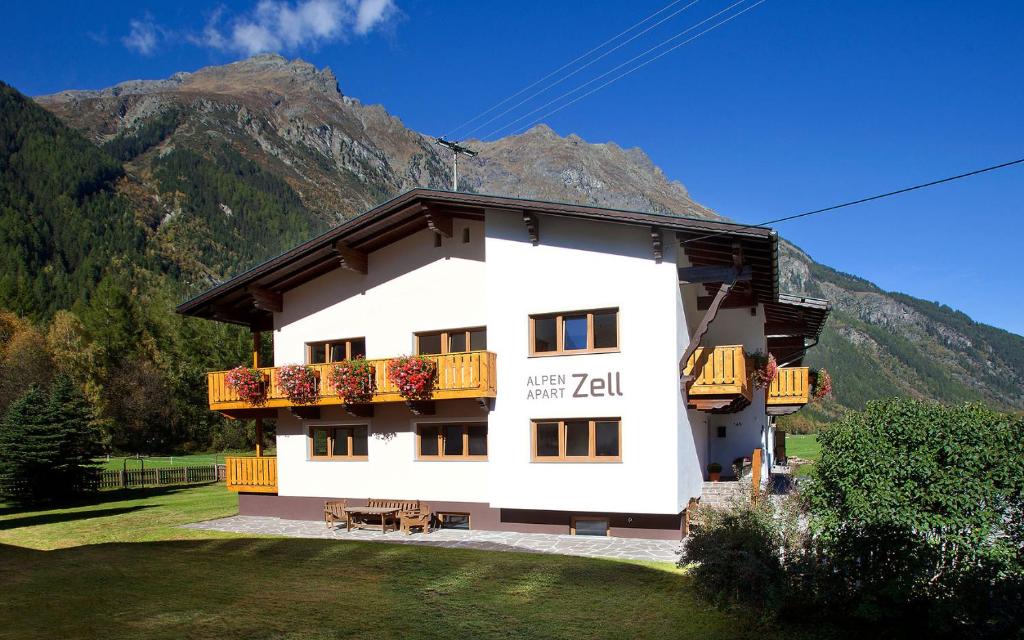a white building with a balcony and mountains in the background at Alpenapart Zell in Längenfeld